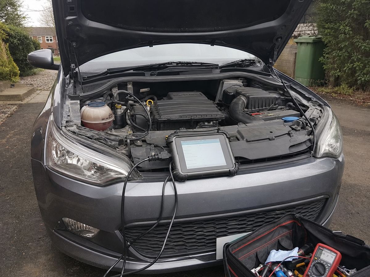 Diagnostic tablet beside an open engine bay during a mobile mechanic visit